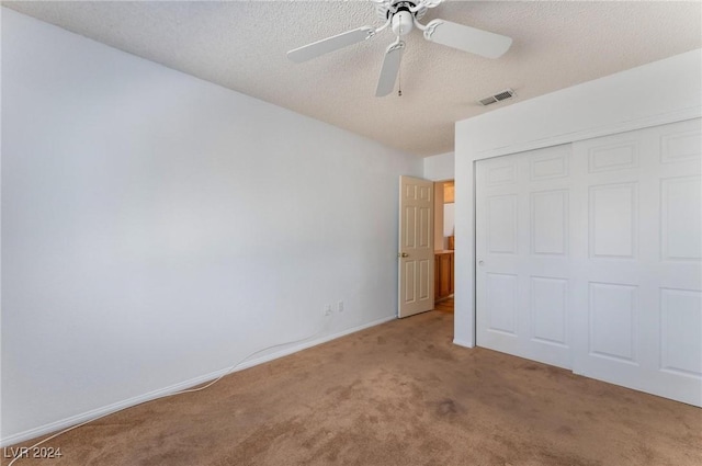 unfurnished bedroom featuring ceiling fan, carpet flooring, a closet, and a textured ceiling