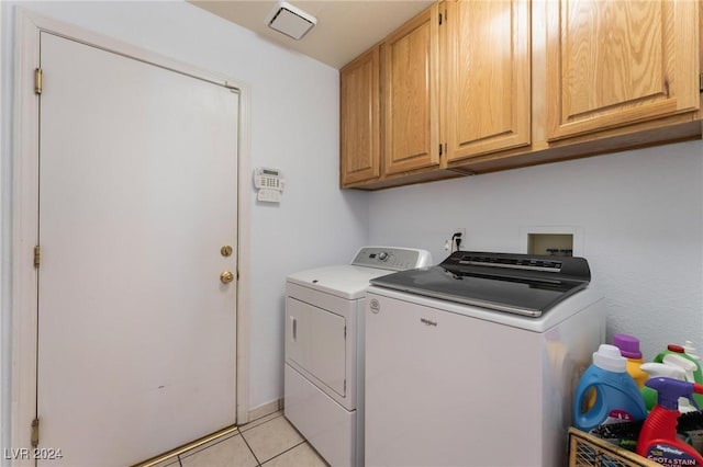 washroom featuring cabinets, light tile patterned floors, and washing machine and clothes dryer