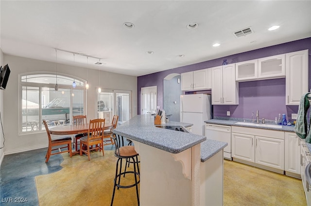 kitchen with sink, decorative light fixtures, white appliances, white cabinetry, and a breakfast bar area