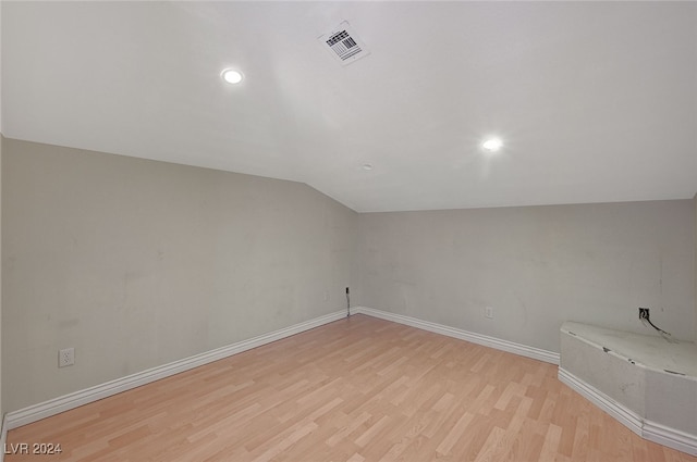 additional living space with light hardwood / wood-style floors and vaulted ceiling