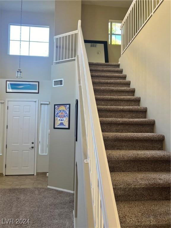 stairs with a towering ceiling and carpet floors