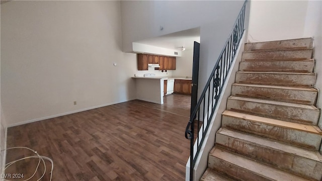 staircase with wood-type flooring and a high ceiling