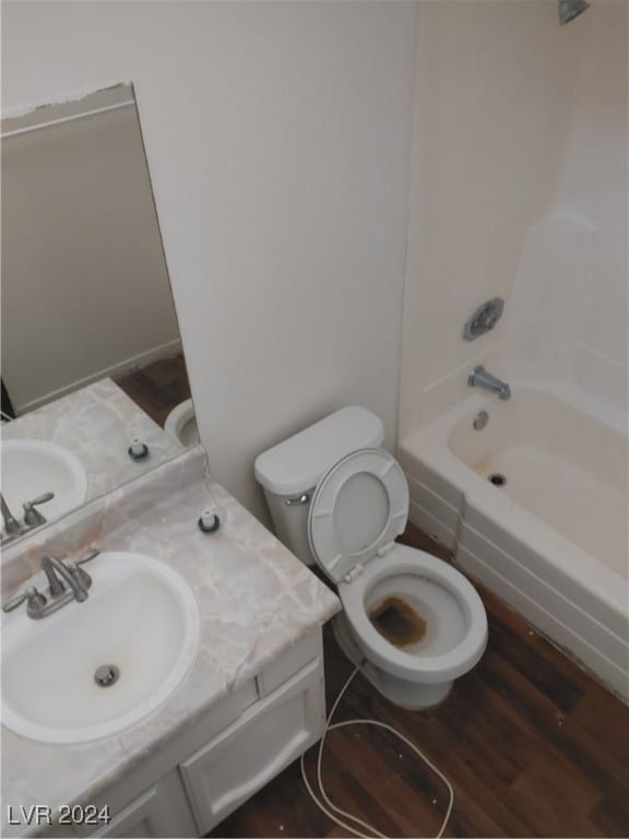 full bathroom featuring washtub / shower combination, hardwood / wood-style flooring, vanity, and toilet