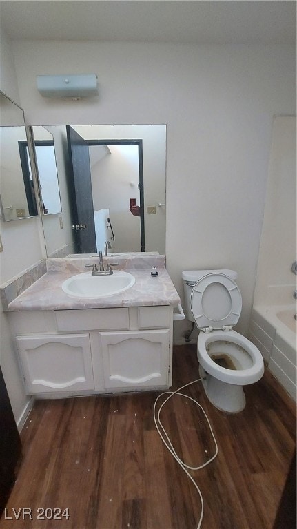 bathroom with a bathtub, wood-type flooring, vanity, and toilet