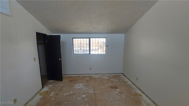 unfurnished bedroom featuring a textured ceiling and lofted ceiling