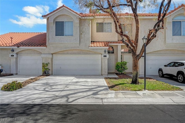 view of front of property with driveway, a tile roof, an attached garage, and stucco siding