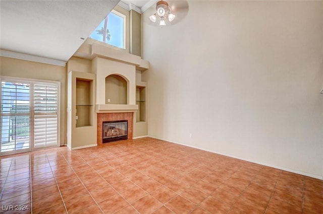 unfurnished living room featuring built in shelves, ornamental molding, light tile patterned flooring, a tile fireplace, and baseboards