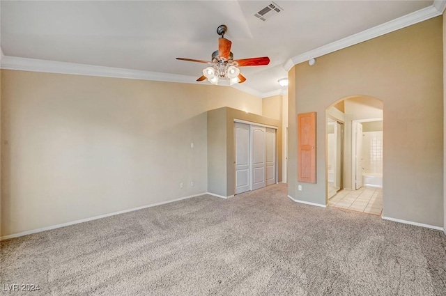 unfurnished bedroom featuring arched walkways, light carpet, visible vents, ornamental molding, and a closet