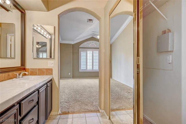 bathroom featuring lofted ceiling, vanity, visible vents, ornamental molding, and tile patterned floors