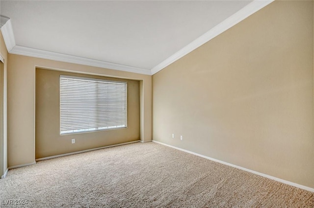 carpeted empty room with baseboards, vaulted ceiling, and crown molding