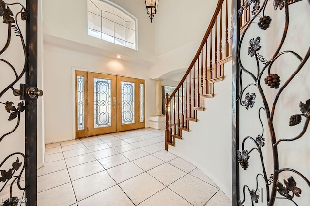 foyer with french doors, decorative columns, plenty of natural light, and a high ceiling