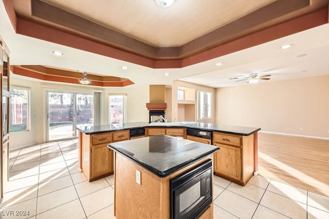 kitchen featuring light tile patterned flooring, a raised ceiling, a kitchen island, kitchen peninsula, and black microwave