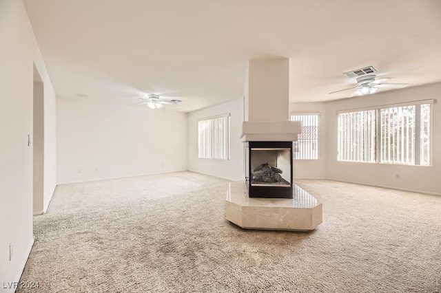 unfurnished living room with carpet, ceiling fan, and a multi sided fireplace