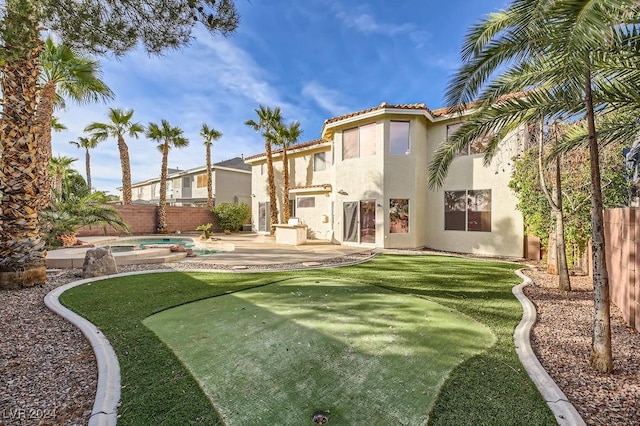 rear view of house featuring an in ground hot tub and a patio