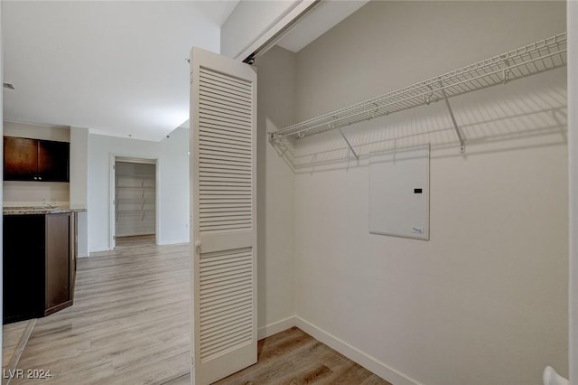 laundry area with light wood-type flooring and baseboards