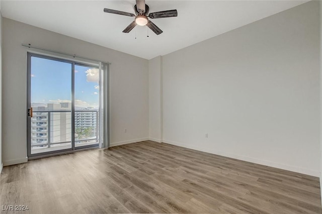 spare room with ceiling fan, baseboards, a city view, and wood finished floors