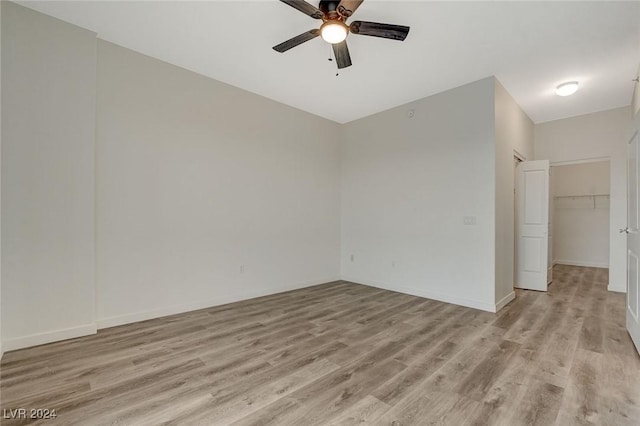 unfurnished bedroom featuring ceiling fan, baseboards, a spacious closet, a closet, and light wood finished floors