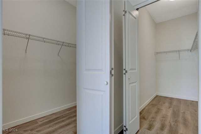 walk in closet with wood finished floors