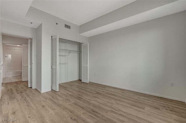 unfurnished bedroom with baseboards, light wood-style flooring, visible vents, and a closet