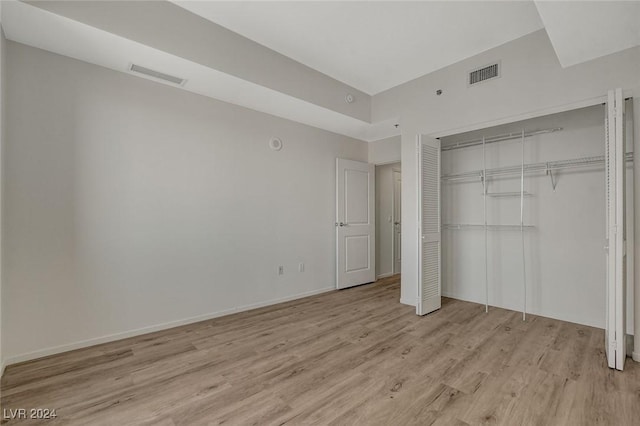 unfurnished bedroom with light wood finished floors, baseboards, visible vents, and a closet