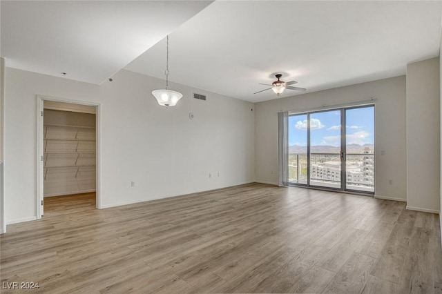 empty room with ceiling fan, baseboards, visible vents, and light wood-style floors