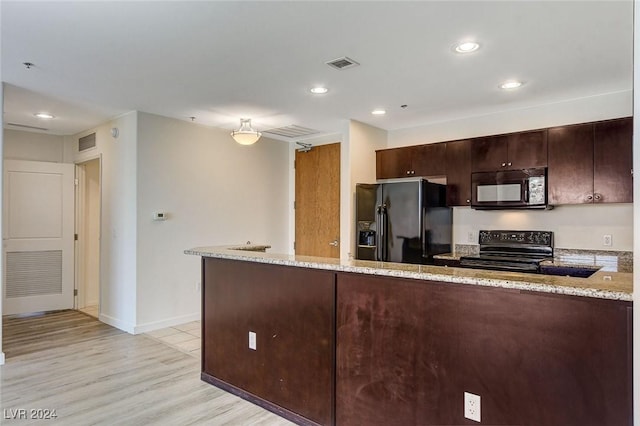 kitchen with light stone counters, visible vents, light wood finished floors, and black appliances