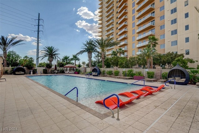 community pool with a patio area and fence