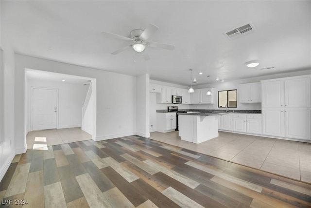 kitchen featuring white cabinets, a center island, light hardwood / wood-style floors, and appliances with stainless steel finishes