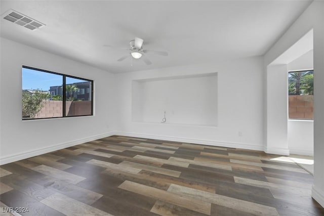 empty room featuring dark hardwood / wood-style floors, ceiling fan, and a healthy amount of sunlight