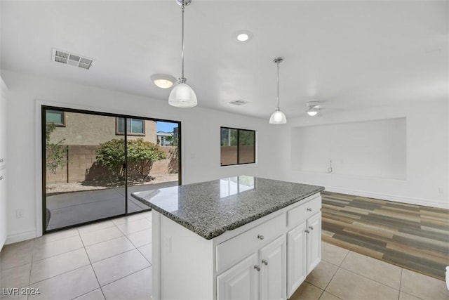 kitchen featuring a center island, hanging light fixtures, dark stone counters, light hardwood / wood-style floors, and white cabinets