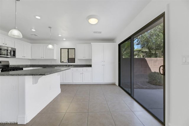 kitchen featuring white cabinetry, hanging light fixtures, dark stone countertops, black range with gas cooktop, and light tile patterned floors