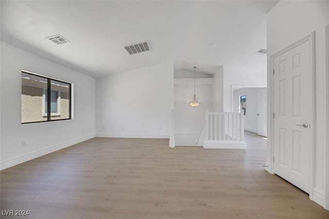 unfurnished room with light hardwood / wood-style floors and vaulted ceiling