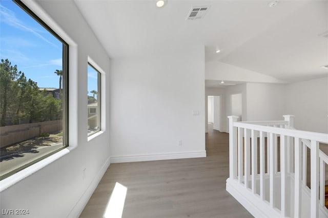 hall featuring hardwood / wood-style flooring and vaulted ceiling