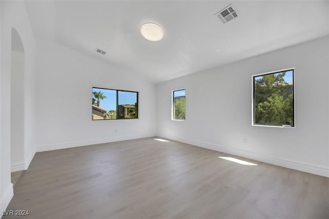 spare room featuring hardwood / wood-style floors and vaulted ceiling