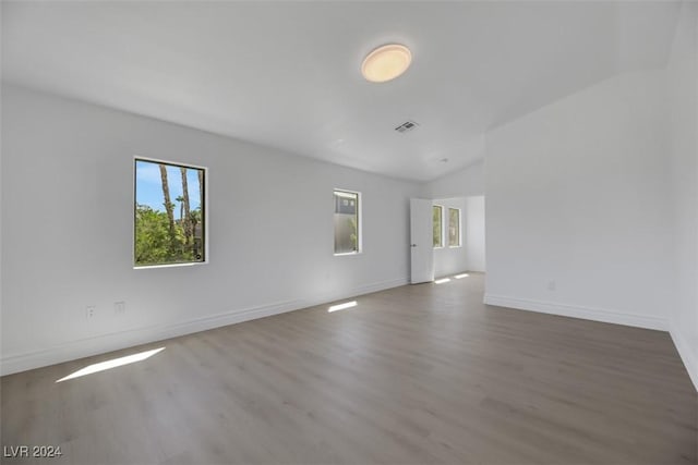 unfurnished room featuring wood-type flooring and vaulted ceiling