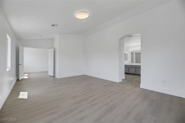 empty room with light hardwood / wood-style floors and lofted ceiling