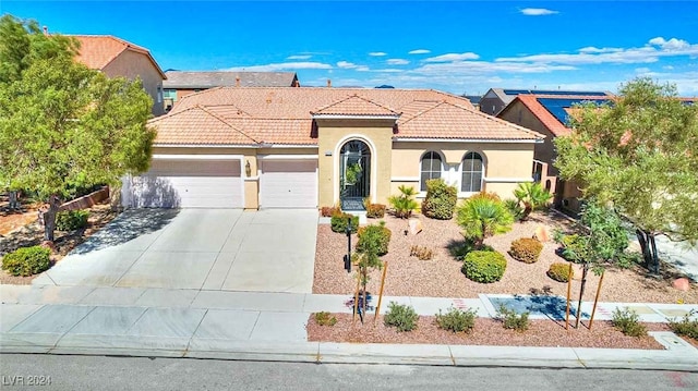 mediterranean / spanish home with driveway, stucco siding, an attached garage, and a tiled roof