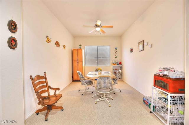 dining space with ceiling fan and light colored carpet