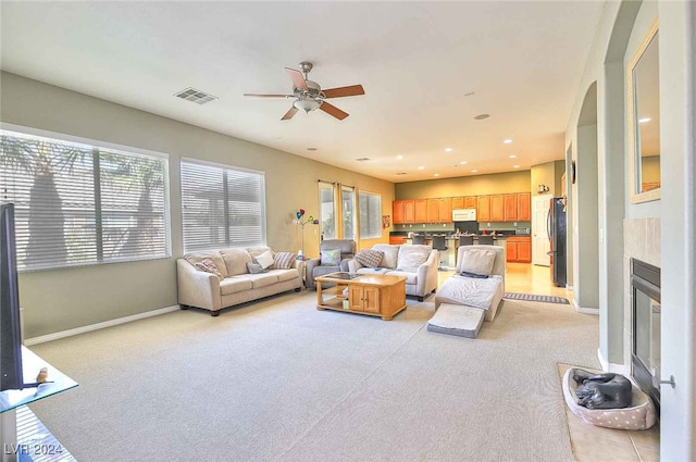 living area with light colored carpet, visible vents, a fireplace, and baseboards