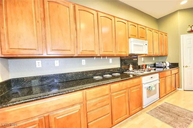 kitchen featuring white appliances and dark stone counters