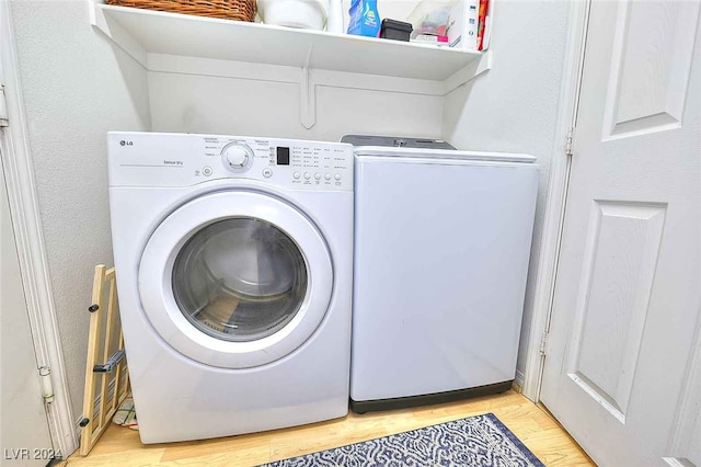 laundry room with laundry area, independent washer and dryer, and light wood finished floors