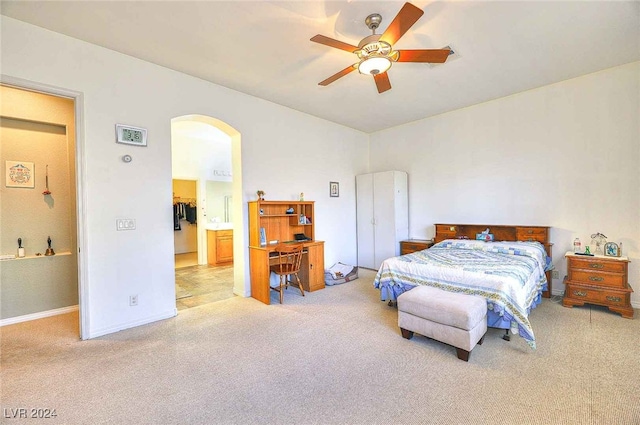 carpeted bedroom featuring a ceiling fan, arched walkways, and baseboards