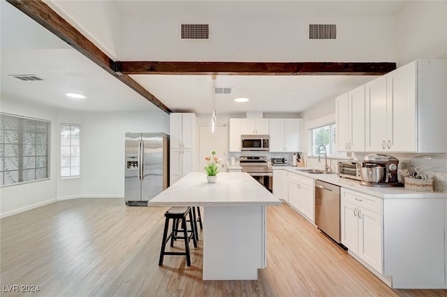 kitchen with stainless steel appliances, light hardwood / wood-style floors, and white cabinetry