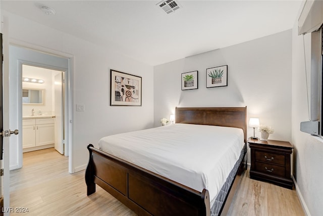 bedroom featuring light wood-type flooring and ensuite bath