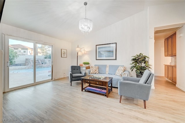 living room with an inviting chandelier, light hardwood / wood-style flooring, and lofted ceiling