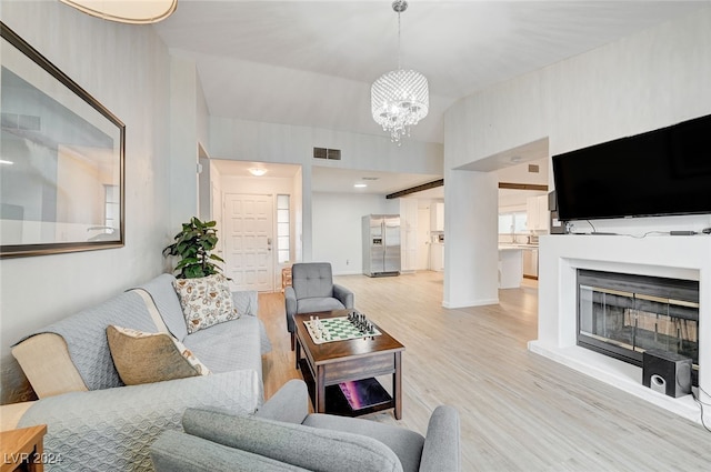 living room featuring a notable chandelier and light wood-type flooring