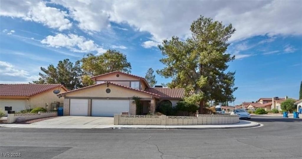 mediterranean / spanish house featuring driveway, a tiled roof, a garage, and stucco siding