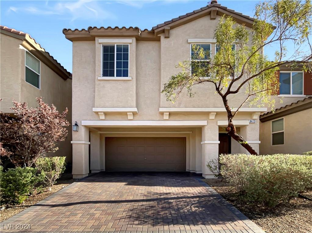 view of front of house featuring an attached garage, a tiled roof, decorative driveway, and stucco siding