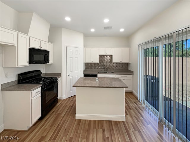 kitchen featuring light hardwood / wood-style flooring, white cabinetry, sink, black appliances, and a kitchen island