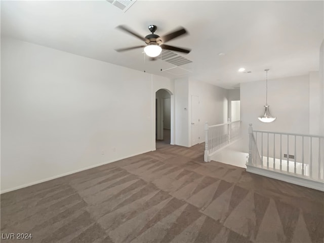 unfurnished room with dark colored carpet and ceiling fan